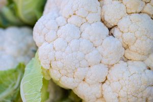 Detailed close-up shot of a fresh cauliflower head with green leaves, showcasing natural texture.